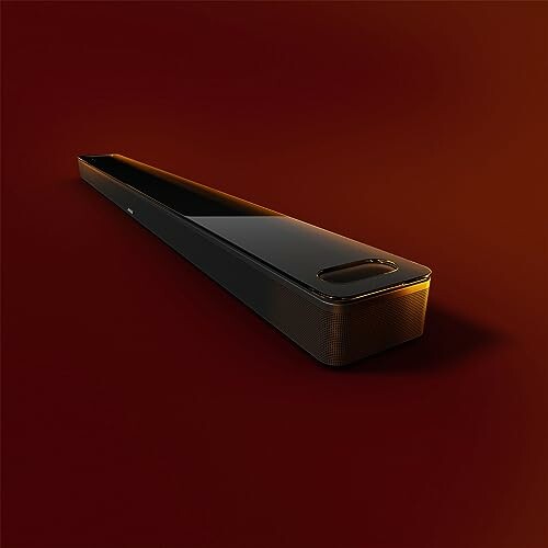 Sleek black soundbar with red background.